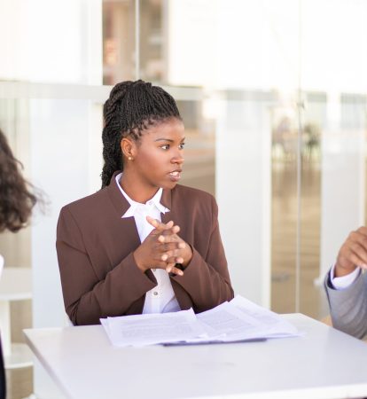 Advisor explaining document details to customers Advisor explaining document details to customers. Multiethnic business man and women sitting at table outdoors and talking. Paperwork or expertise concept