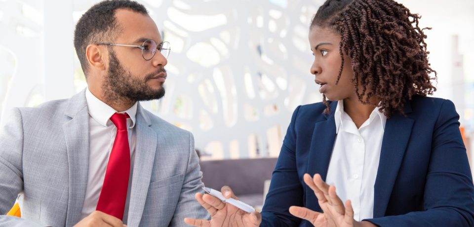 Businessman and businesswoman discussing contract. Young African American business colleagues sitting in office and working with papers. Paperwork concept