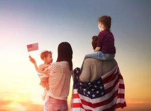 Patriotic holiday. Happy family, parents and daughters children girls with American flag outdoors. USA celebrate 4th of July.